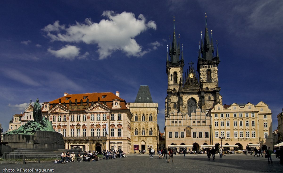 A large square, bustling with passersby and dominated by the palace and the church under a blue sky