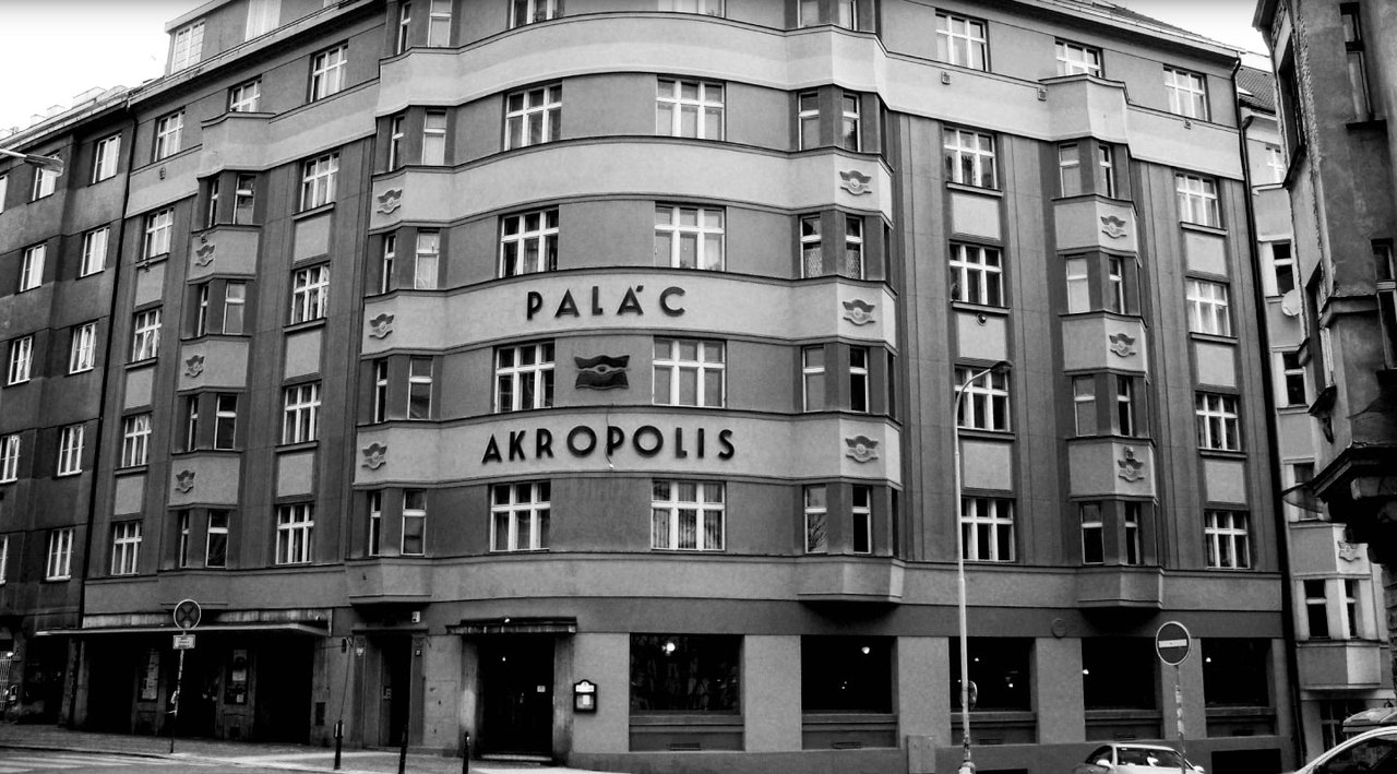 The facade of a large corner building in black and white, with numerous windows lined up across several stories