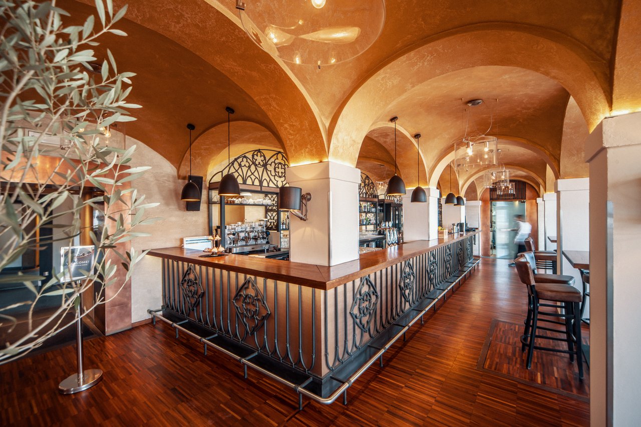 A bar in a restaurant with a vaulted ceiling and white pillars
