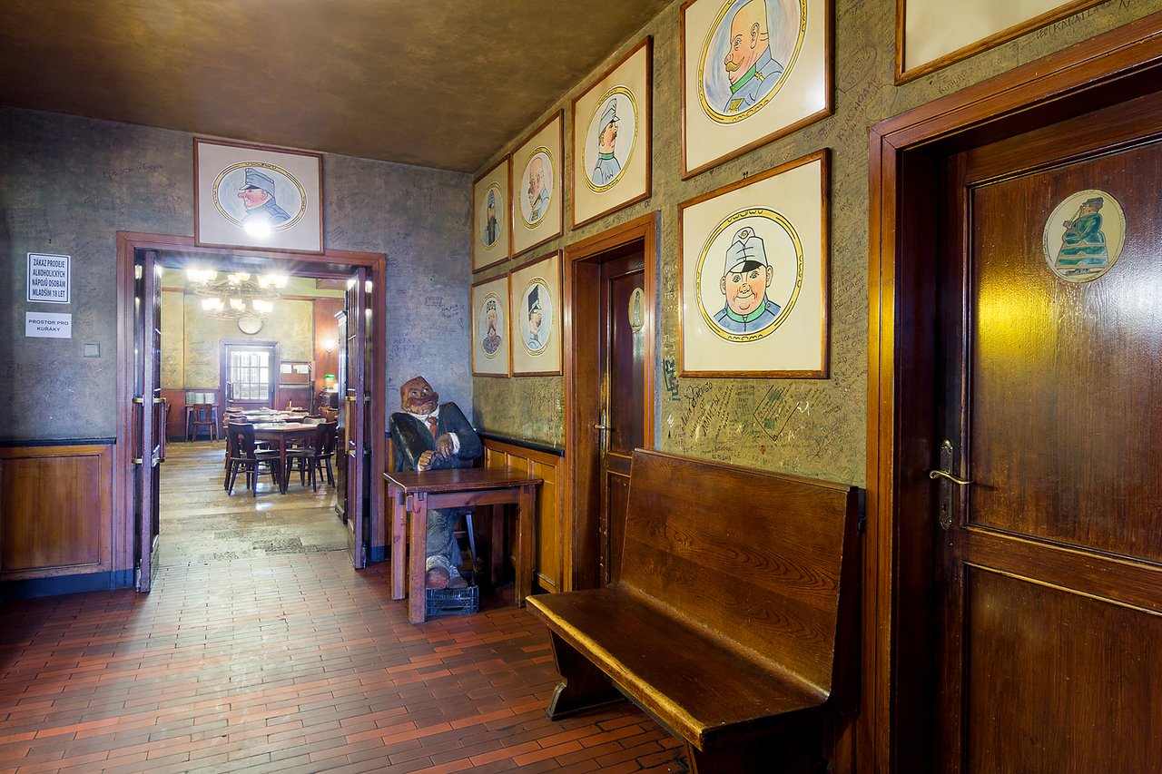 A wall covered with quotes and paintings, there is a statue in the background and a dining room in the back room